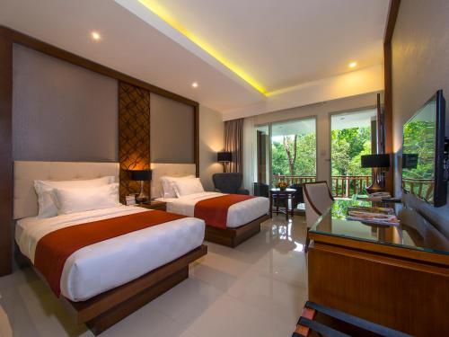 马格朗Puri Asri Hotel & Resort的酒店客房配有两张床和一张书桌