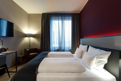 海德堡Qube Hotel Bahnstadt的一间设有大床和窗户的酒店客房