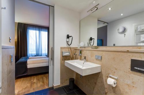 海德堡Qube Hotel Bahnstadt的一间带水槽和镜子的浴室