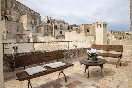 马泰拉L'Artiere Dimore nei Sassi的阳台设有2张长椅和鲜花桌。