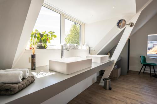 登堡Gravenstraat的一间带白色水槽和窗户的浴室