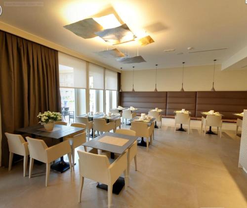 格拉多玫特洛普雷酒店的用餐室配有桌子和白色椅子