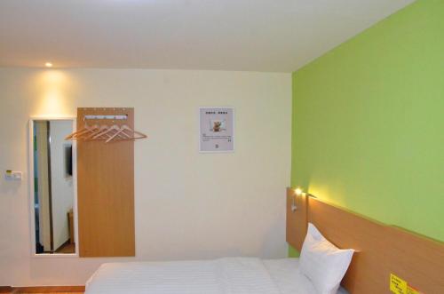 乌鲁木齐7天酒店·乌鲁木齐幸福路大巴扎店的一间卧室设有一张床和绿色的墙壁