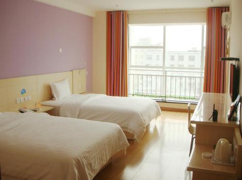 榆林7天酒店·榆林广济大厦店的酒店客房设有两张床和窗户。