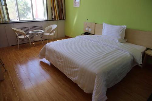 哈密7天酒店·哈密宝丰市场店的卧室配有白色的床和桌椅