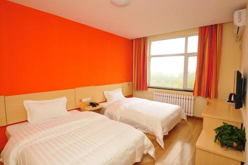 Huadian7天酒店·德州齐河客运中心店的一间卧室设有两张床和橙色的墙壁