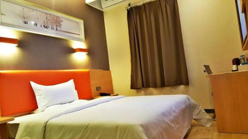 涪陵7天优品·重庆涪陵滨江大道店的一间卧室配有一张白色大床和橙色床头板