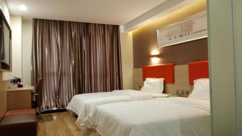 唐山7天优品·唐山新华西道理工大学店的酒店客房设有两张床和窗户。
