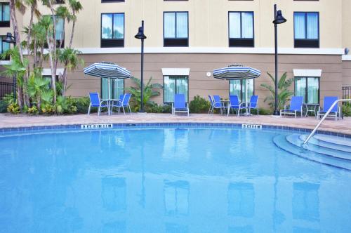 奥兰多Holiday Inn Express-International Drive, an IHG Hotel的一个带椅子和遮阳伞的大型游泳池