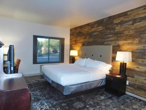 派托普湖畔GreenTree Inn & Suites Pinetop的一间卧室设有一张床和木墙