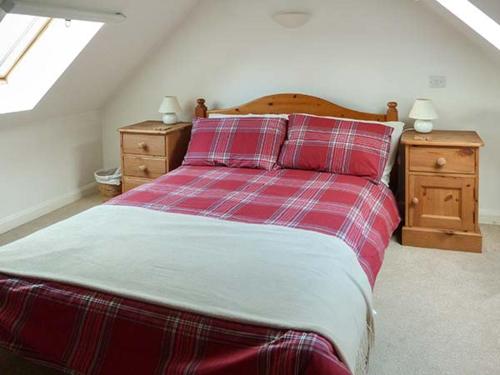 唐尼Creag Mhor Cottage的一张红色和白色的床,房间有两个床头柜