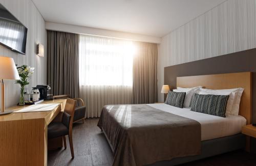 阿尔马达阿尔马达里斯本美居酒店的配有一张床和一张书桌的酒店客房