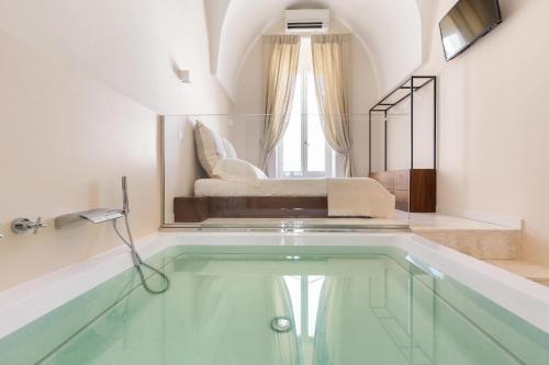 奥斯图尼Palazzo Mascetti Executive Rooms的一个带游泳池的客房,后面设有一张床