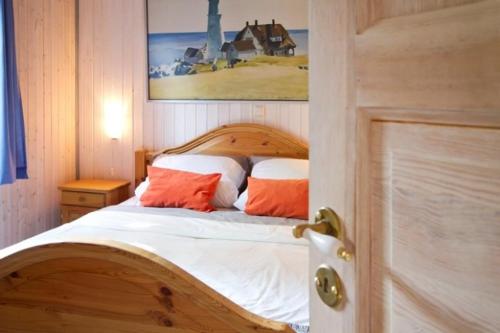 米罗Ferienhaus 67 am Granzower See的一间卧室配有一张带两个橙色枕头的木床