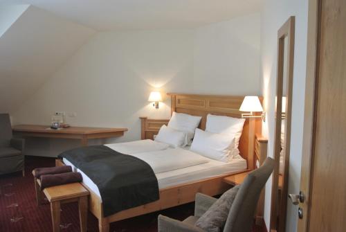 魏贝尔斯布伦Hotel Jägerhof的一间卧室配有一张床、一张桌子和一把椅子