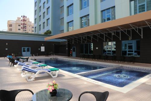 麦纳麦The Olive Hotel, Juffair的一座带躺椅的游泳池和一座建筑