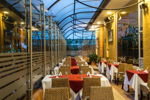 波哥大Hotel Regency Boutique La Feria的一间带桌椅和玻璃天花板的用餐室