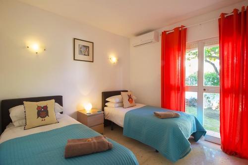 马贝拉Villa Linda Vista的一间卧室配有两张带红色窗帘的床和窗户。