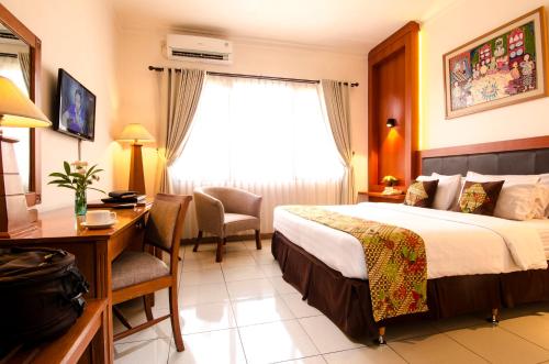 日惹Griya Sentana Hotel的配有一张床、一张书桌和一扇窗户的酒店客房
