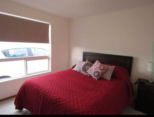 纳塔列斯港Greyhouse的一间卧室配有一张带红色棉被的床和窗户。