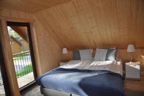 博尔斯克Domki Largo nad Jeziorem Wdzydze的木制客房内的一间卧室,配有一张床