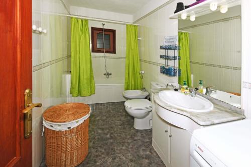 蒂哈拉费Casa Lorenzo的一间带水槽、卫生间和绿色窗帘的浴室