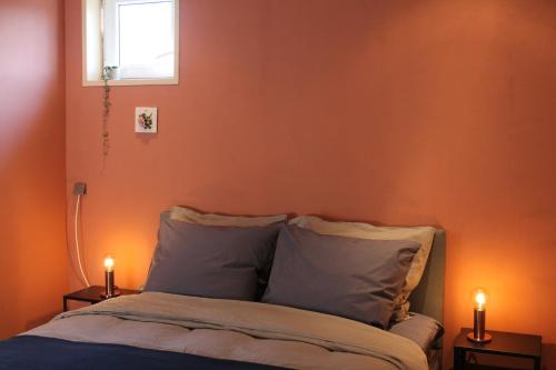 多廷赫姆Gastenverblijf Peppelmate的一间卧室设有橙色的墙壁和一张带两个蜡烛的床。