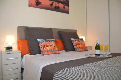 圣地亚哥德拉里贝拉El Mirador de la Ribera - 7408的一间卧室配有一张带橙色枕头的床和一瓶葡萄酒。