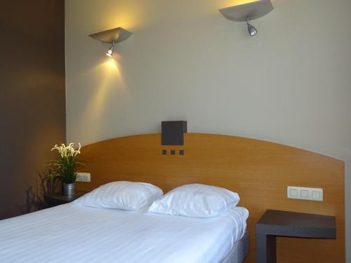 布鲁塞尔布鲁塞尔世博超值住宿酒店的一间卧室配有一张带木制床头板的床和两个枕头