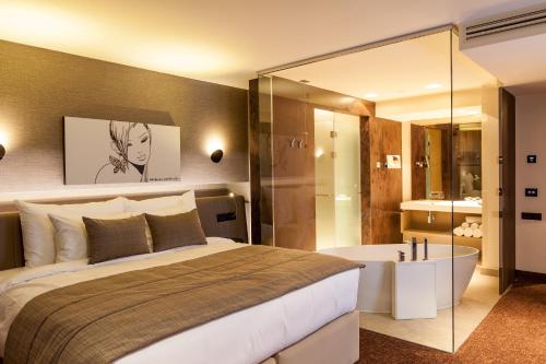 布拉索夫可龙威尔布拉索夫酒店的一间卧室设有一张大床和一个浴缸