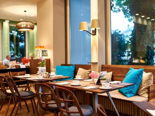 萨尔茨堡Boutique Hotel & Villa AUERSPERG的餐厅设有木桌、椅子和窗户