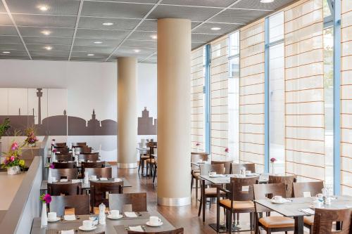 多特蒙德NH多特蒙德酒店的餐厅设有桌椅和窗户。