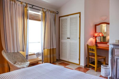 塔维拉雷伊谷客栈的一间卧室配有一张床、一张书桌和一个窗户。