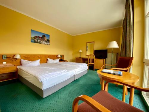施特雷利茨Park Hotel Fasanerie Neustrelitz的酒店客房设有一张大床和一张桌子。