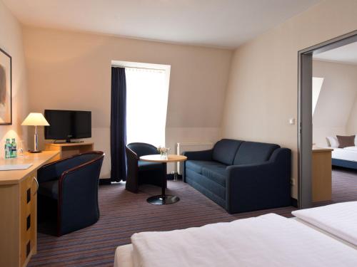德累斯顿ACHAT Hotel Dresden Elbufer的酒店客房配有床、沙发和电视。