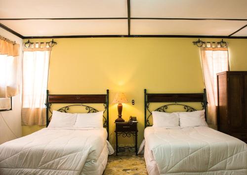 圣萨尔瓦多圣塔埃伦娜酒店的一间卧室配有两张带白色床单的床