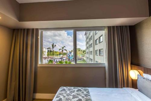 阿蒂巴亚Tauá Hotel & Convention Atibaia的一间卧室设有窗户,享有城市美景