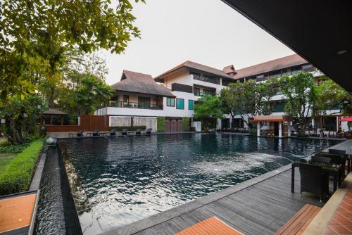 清迈RatiLanna Riverside Spa Resort的大楼前的游泳池