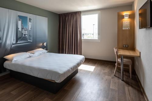 特鲁瓦B&B HOTEL Troyes Magasins d'usine的配有一张床、一张书桌和一扇窗户的酒店客房