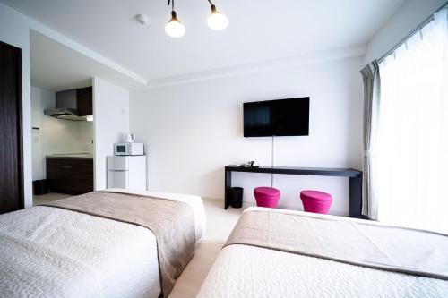 大阪Roof Hanazonocho-Nishi的一间卧室设有两张床,墙上配有电视。