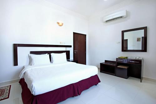塞拉莱Star Emirates Furnished Apartment的白色卧室设有一张大床和镜子
