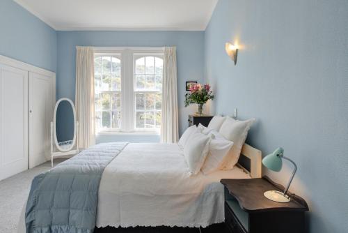 惠灵顿Thorndon Heritage Listed Villa的蓝色的卧室设有一张大床和一个窗户