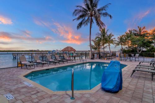 皮尔斯堡Hutchinson Island Hotel的一个带椅子和棕榈树的度假村游泳池