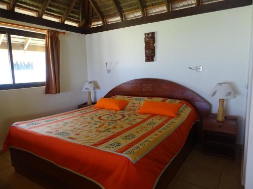 Opoa阿提亚皮逖酒店的一间卧室配有一张带橙色棉被和两盏灯的床。