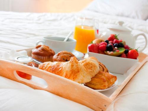 纳皮尔Thistle B&B的床上的早餐托盘,包括糕点和水果