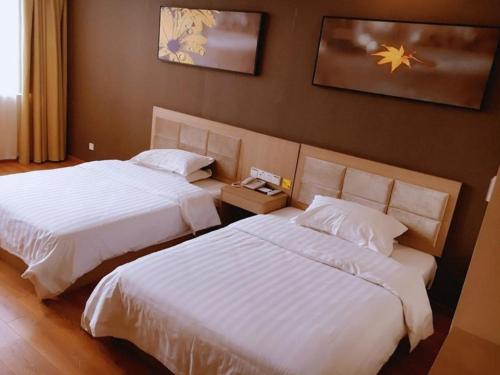 盐城7天酒店·盐城建湖秀夫南路店的配有白色床单的酒店客房内的两张床