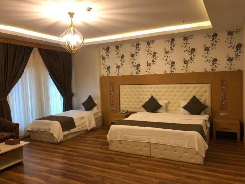 埃尔比勒埃尔比勒克莱西酒店的一间卧室配有两张床和吊灯。