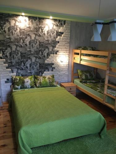 文茨皮尔斯Pie ābeles的一间卧室设有绿色的床和砖墙