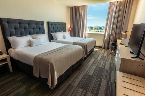 奇廉MDS Hotel Chillan的酒店客房设有两张床和一台平面电视。