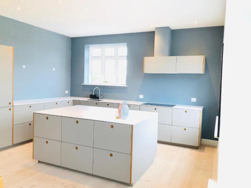 奥尔堡aday - 4 Bedroom - Modern Living Apartment - Aalborg的厨房配有白色橱柜和蓝色的墙壁